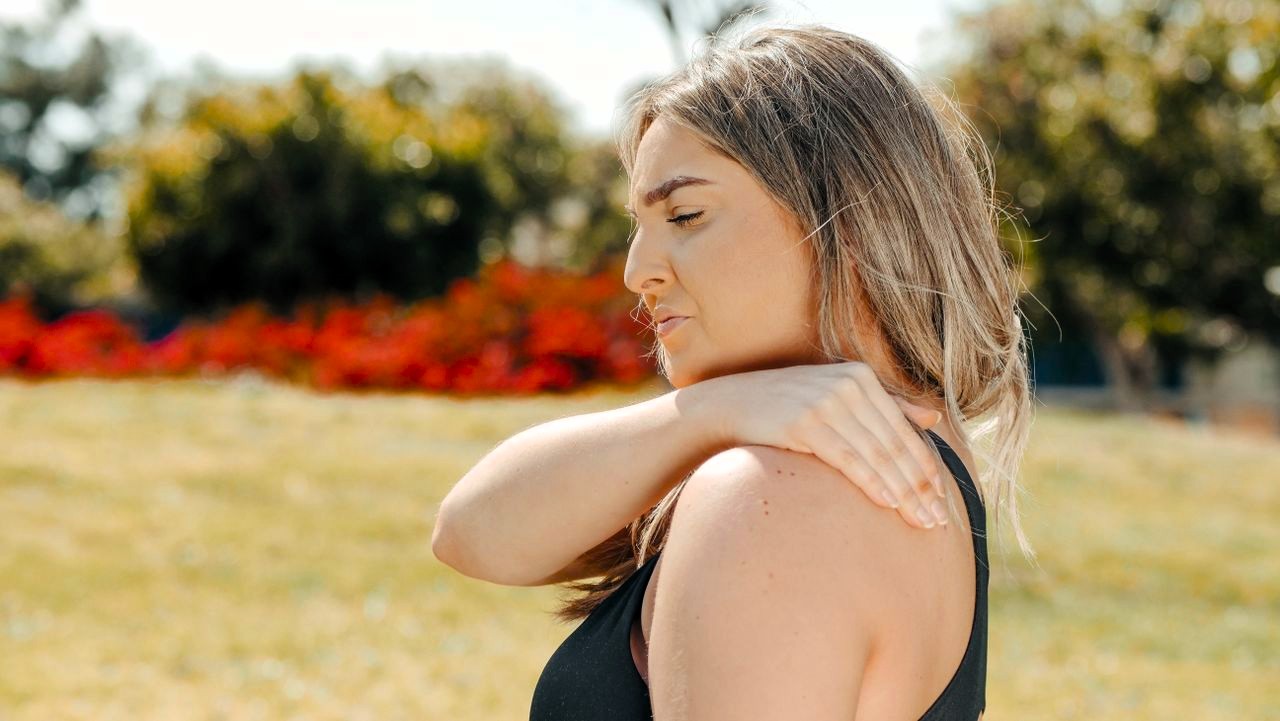 Woman touching her shoulder due to tendinitis pain